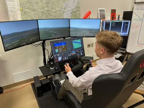 Person using a flight simulator with multiple screens.