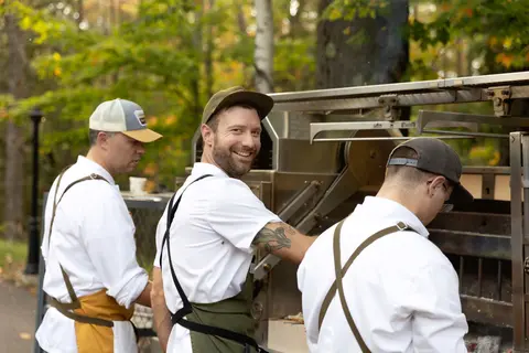 Chefs cooking on an outdoor grill.