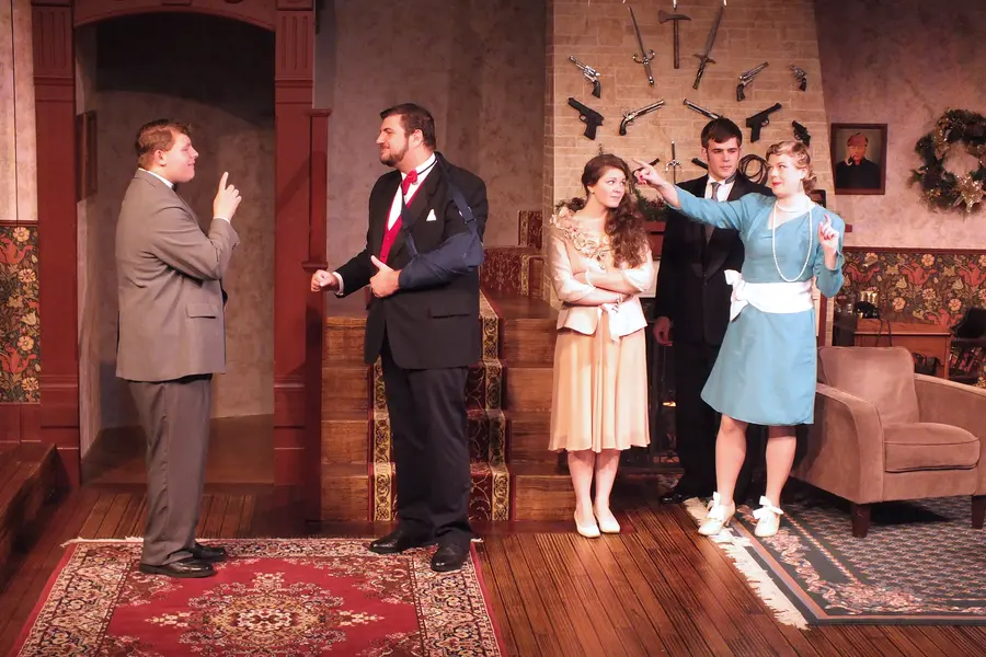 Stage play scene with five actors in a living room setting.