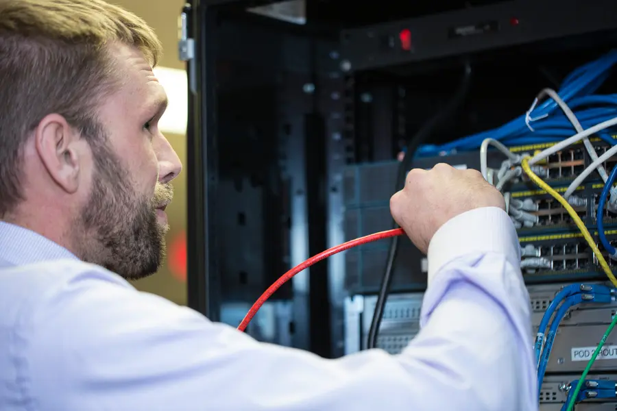 Male IT student working with cables.