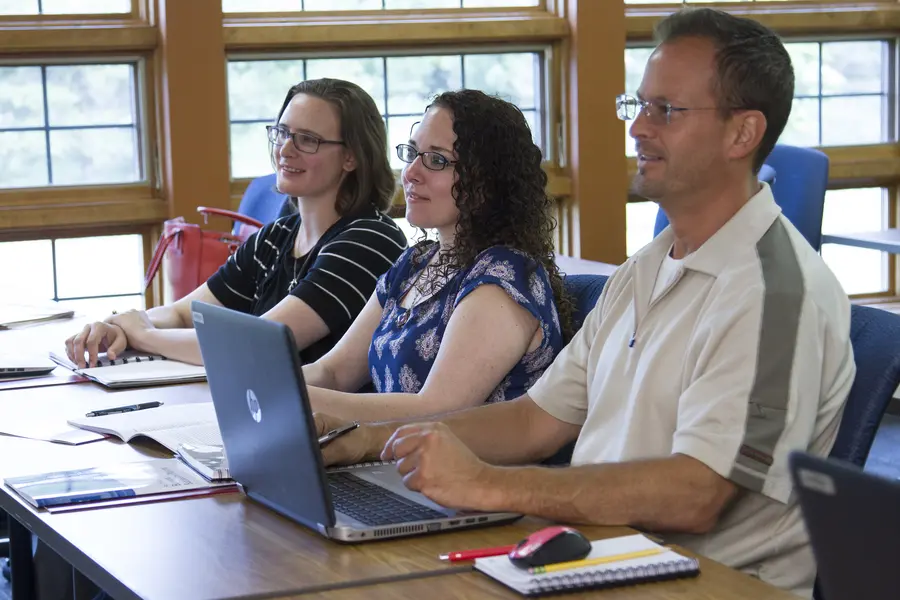 People sitting at a table during a Grow North meeting, with laptops and notebooks.