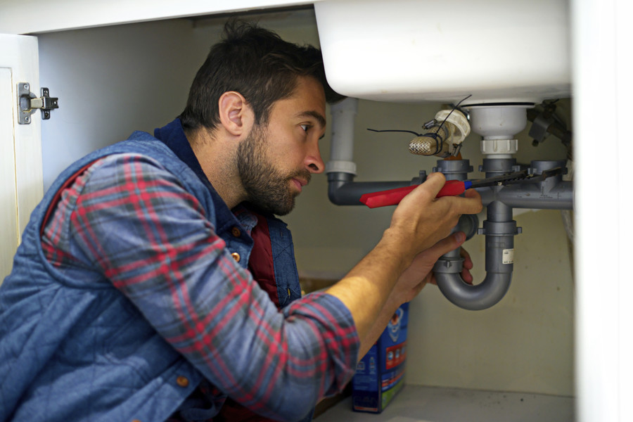 Plumber fixing piping under sink