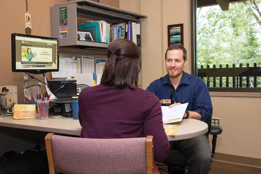 Female student meeting with financial aid representative in office setting.