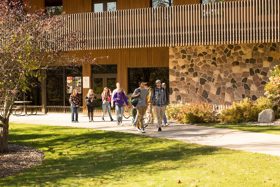 Students walking out of the Red Oak Center on a sunny path.