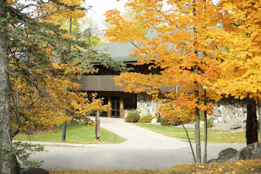 Pathway leading to the Red Oak Center building framed by vibrant orange fall trees.