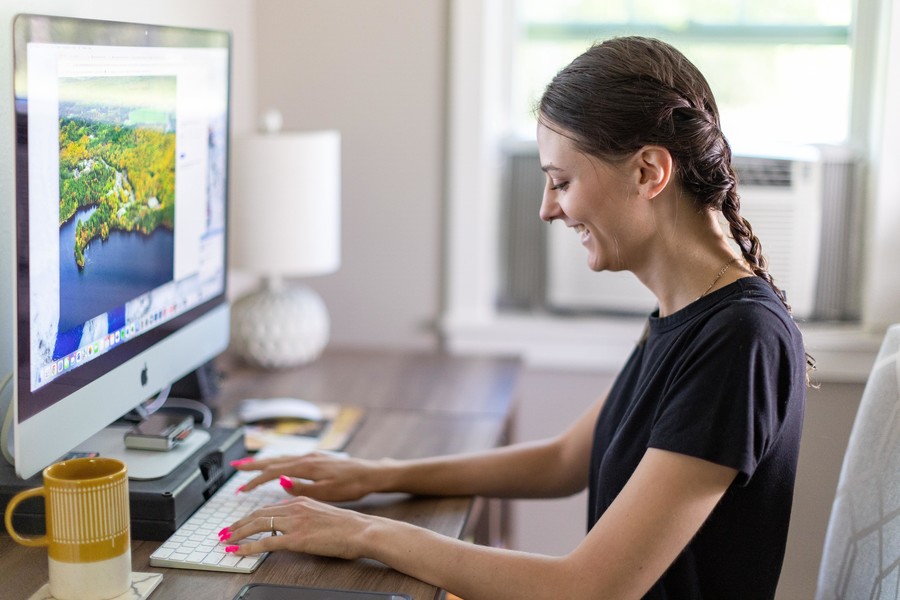 female student working on computer at home smiling