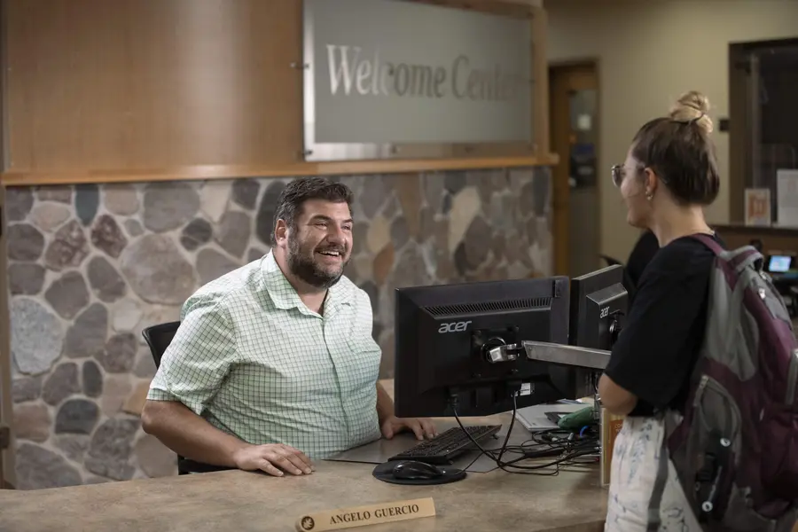 Female student talking with smiling Welcome Center staff member.