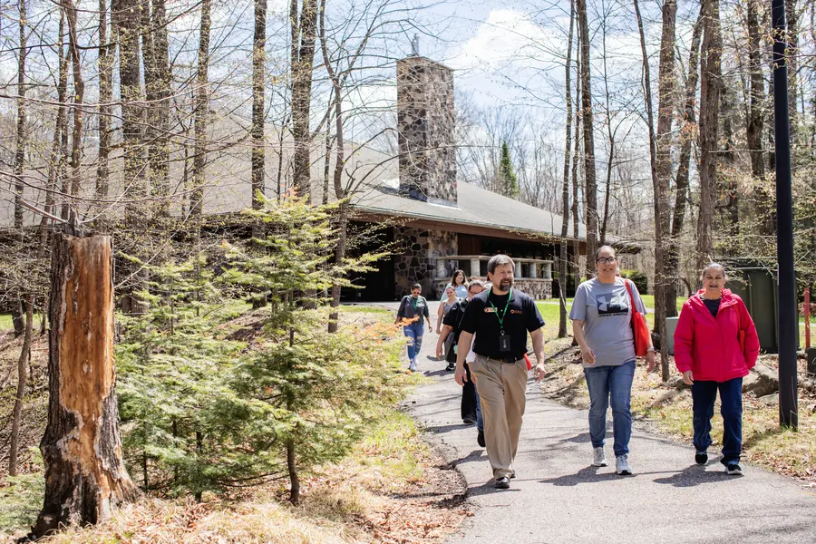 Admissions Representative giving a campus tour to a group of students outside under sunny skies.