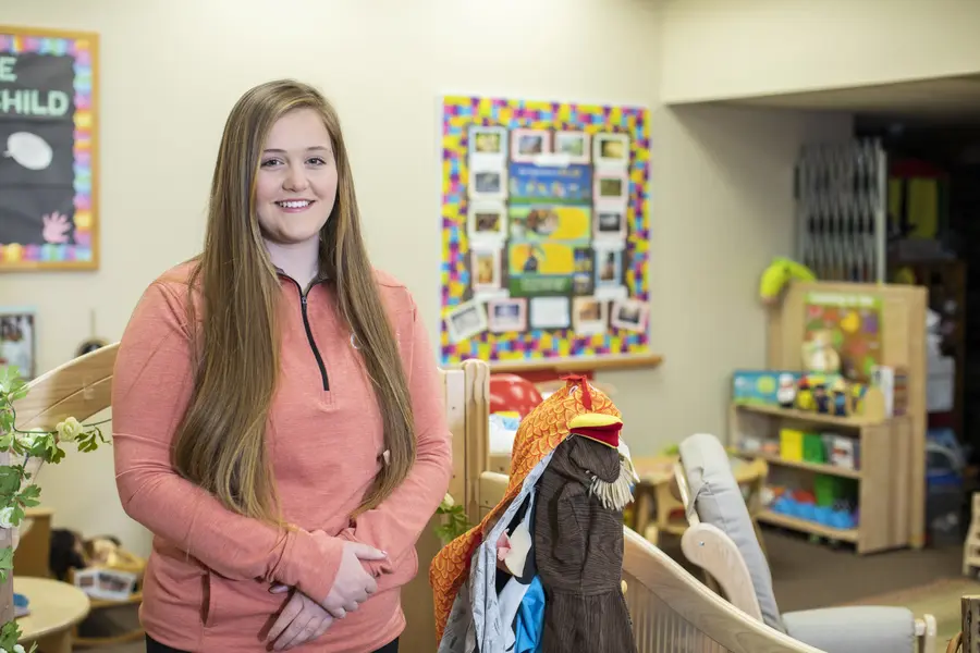 Woman in a classroom setting with educational posters and toys.