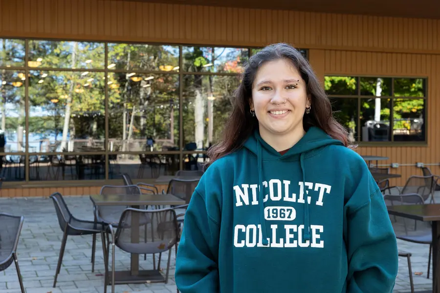 Female student smiling at the camera outside in a Nicolet College sweatshirt