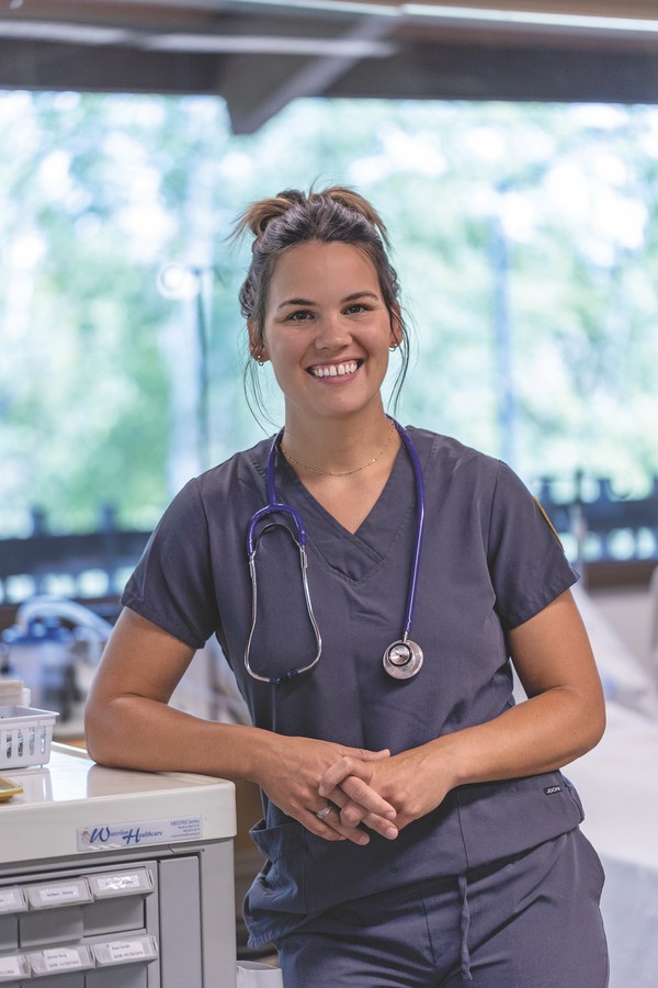 female nursing student in scrubs smiling and posing for photo
